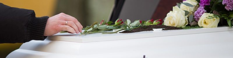 closeup-shot-person-hand-casket-with-blurred-background.jpg